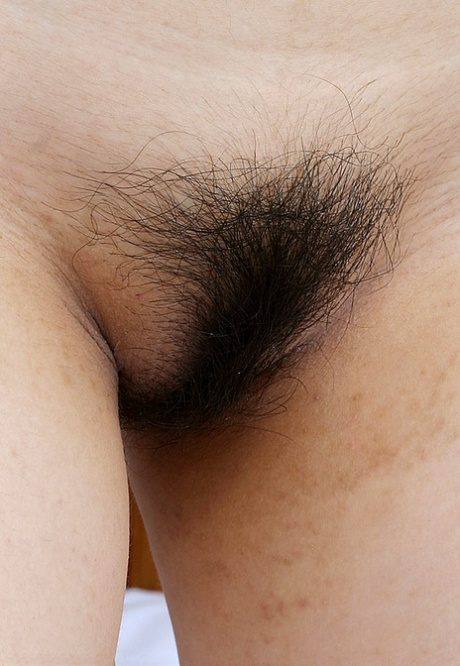 Asian teen spreads her legs on the bed and shows her hairy pussy